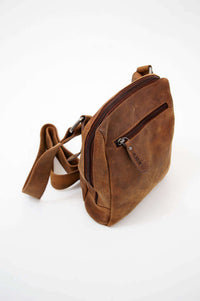 Angled top view of a compact brown leather crossbody bag showcasing its zippered compartments