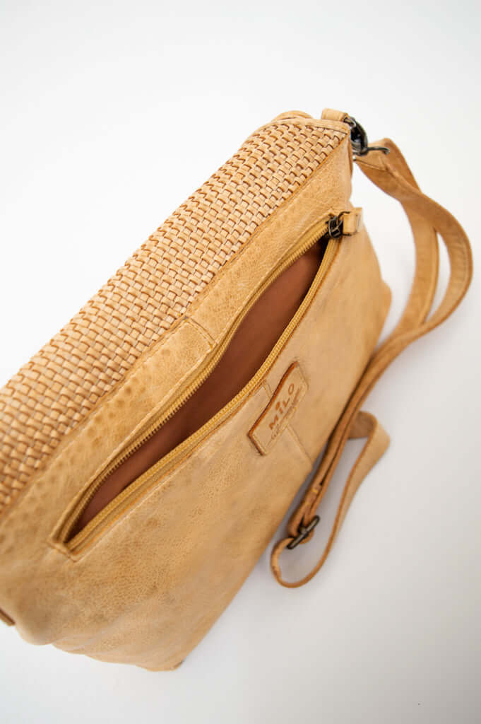 Top view of tan leather crossbody bag showing zippered pocket