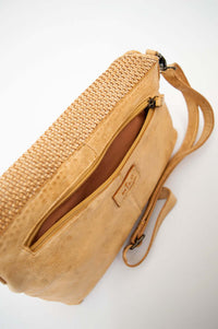 Top view of tan leather crossbody bag showing zippered pocket