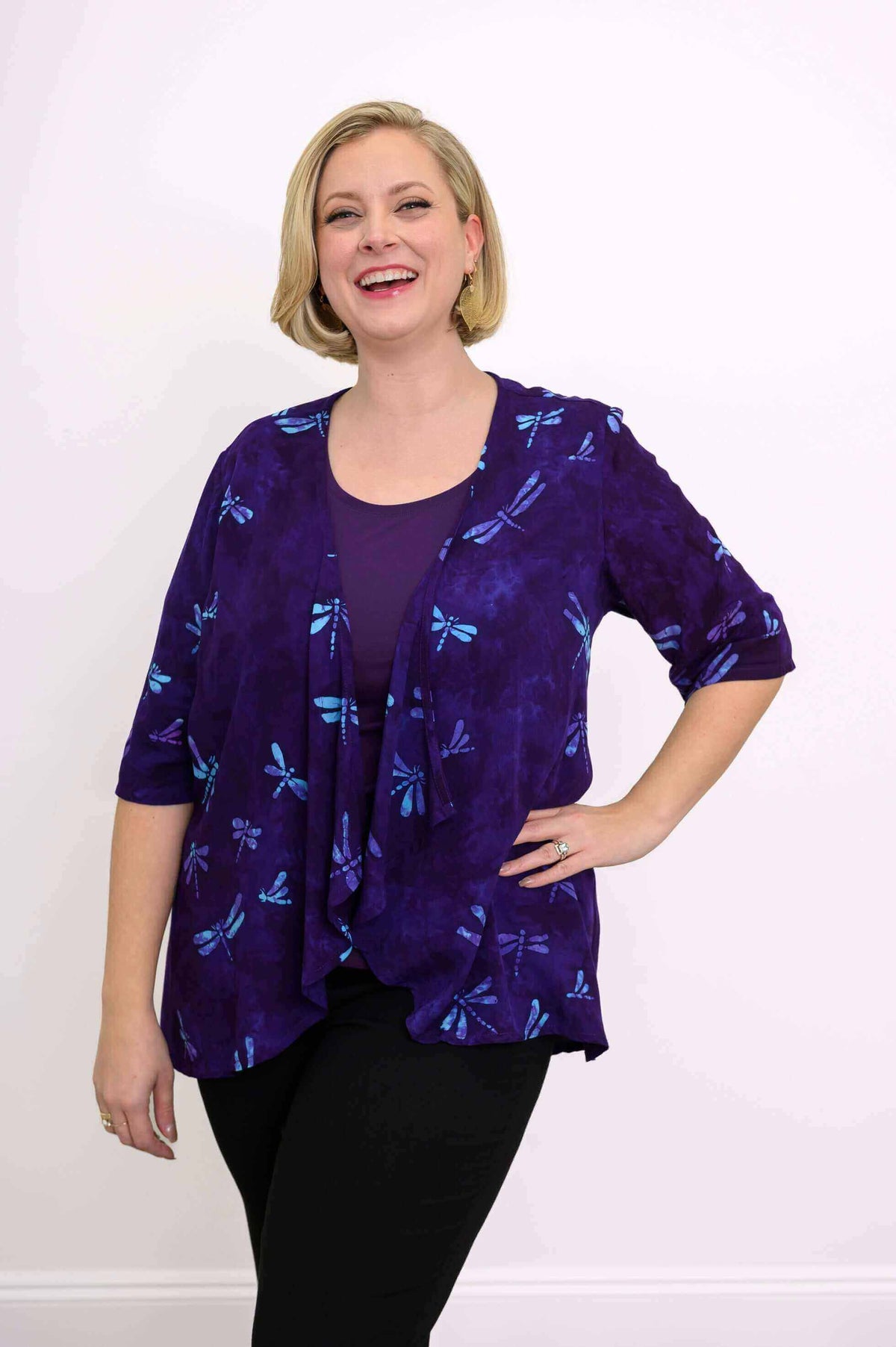 Smiling woman in a purple dragonfly print jacket, hand on hip