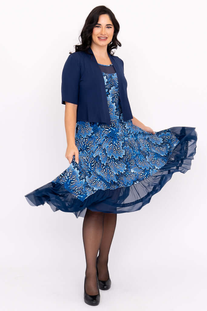 Woman twirling in a blue floral mesh dress paired with a navy shrug