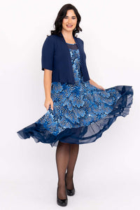 Woman twirling in a blue floral mesh dress paired with a navy shrug