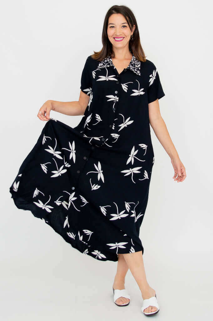 Model twirling in a black A-line button-up dress with white botanical prints