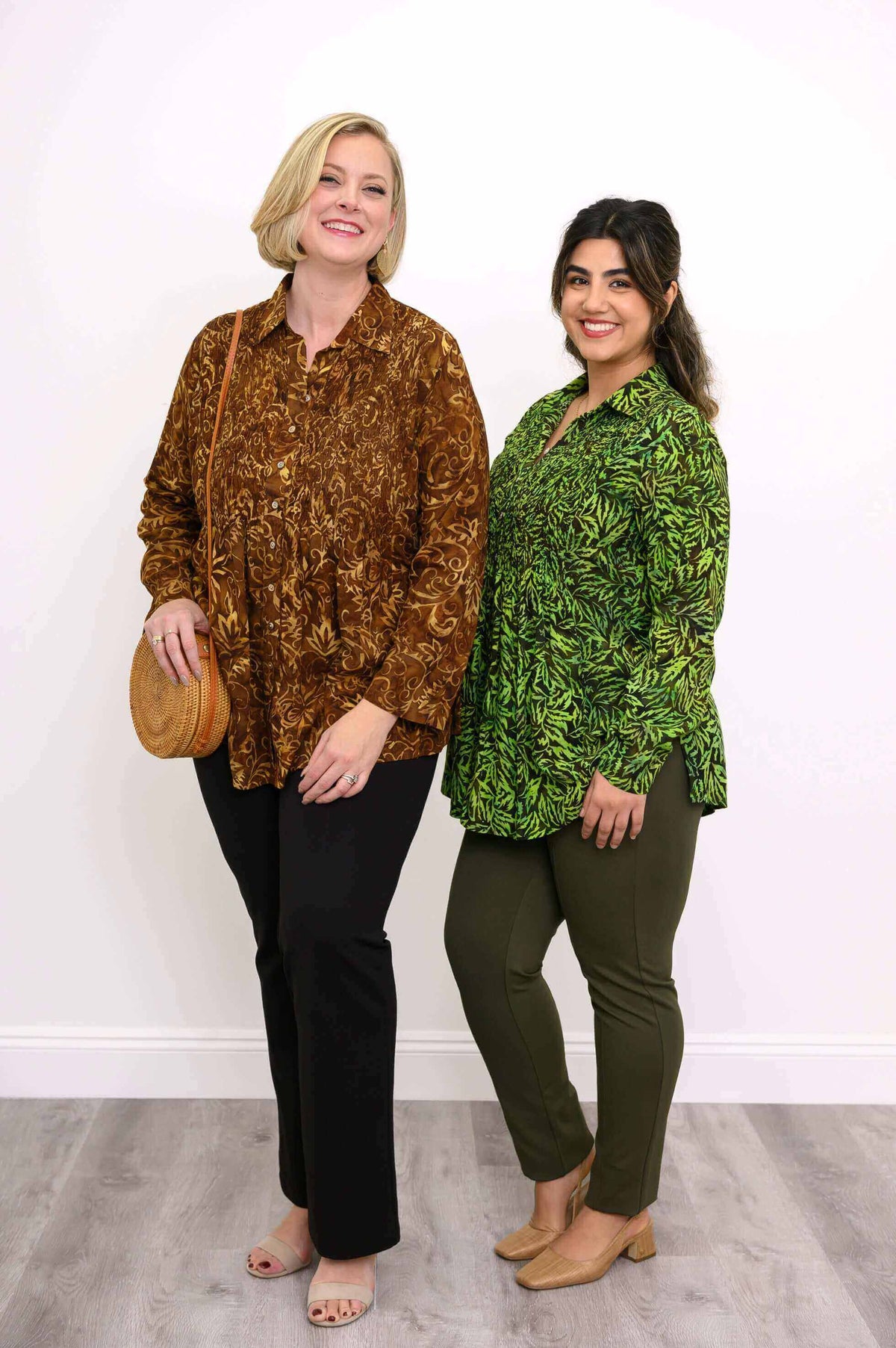 Two women modeling smocked button-up tops in autumn gold and green prints