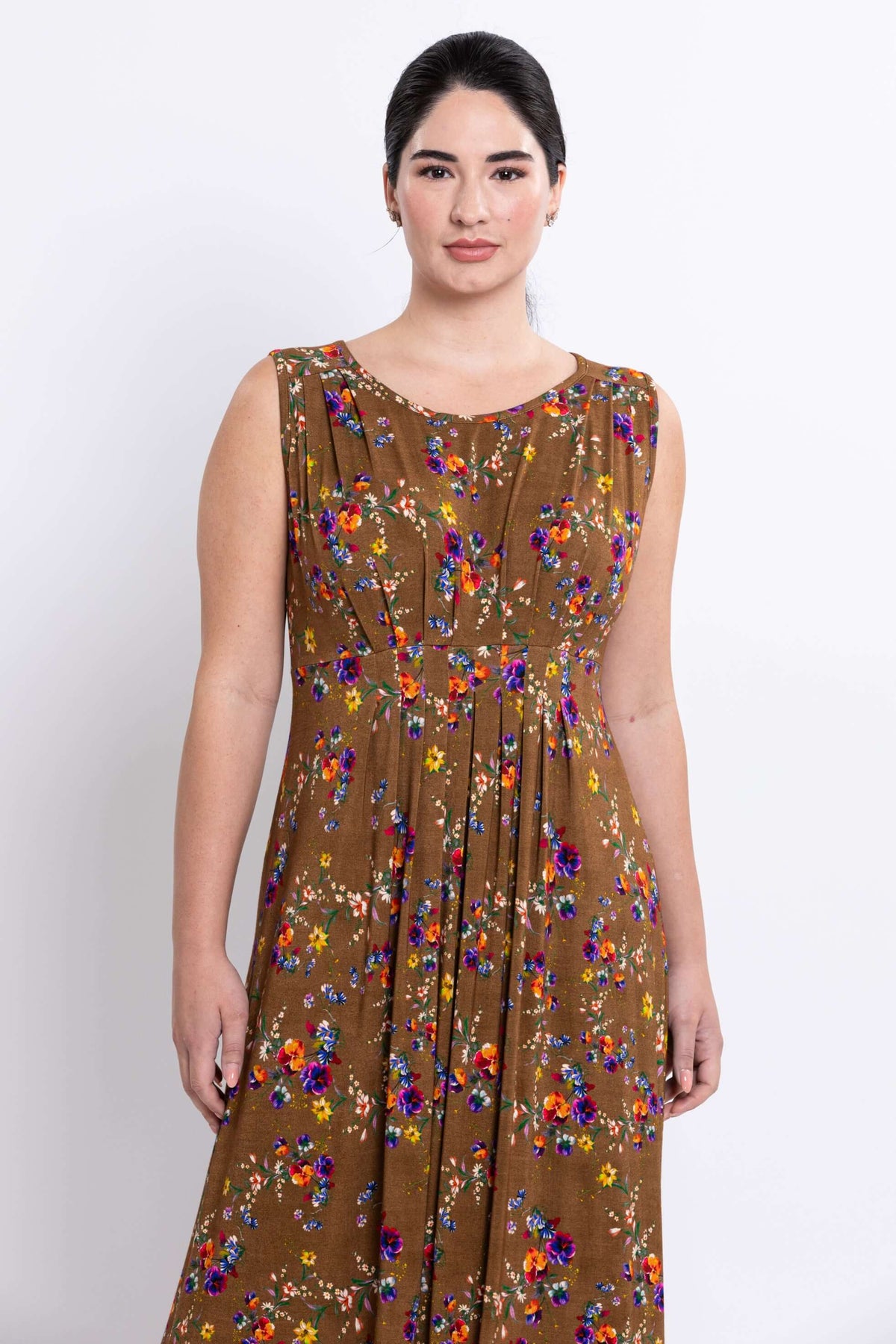Upper front view of a woman in a brown sleeveless maxi dress with colorful floral pattern