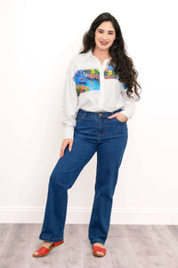 Woman in full-length shot wearing Venice print blouse with jeans and red sandals
