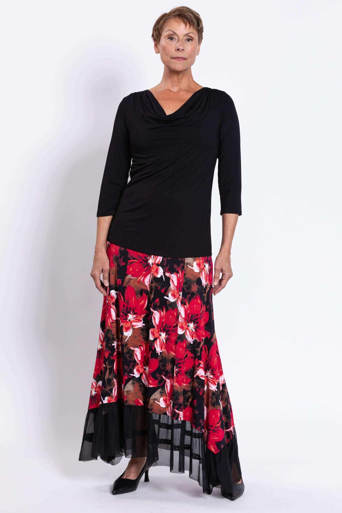 Woman standing in black top and vibrant red floral maxi skirt with mesh trim