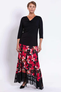 Woman standing in black top and vibrant red floral maxi skirt with mesh trim