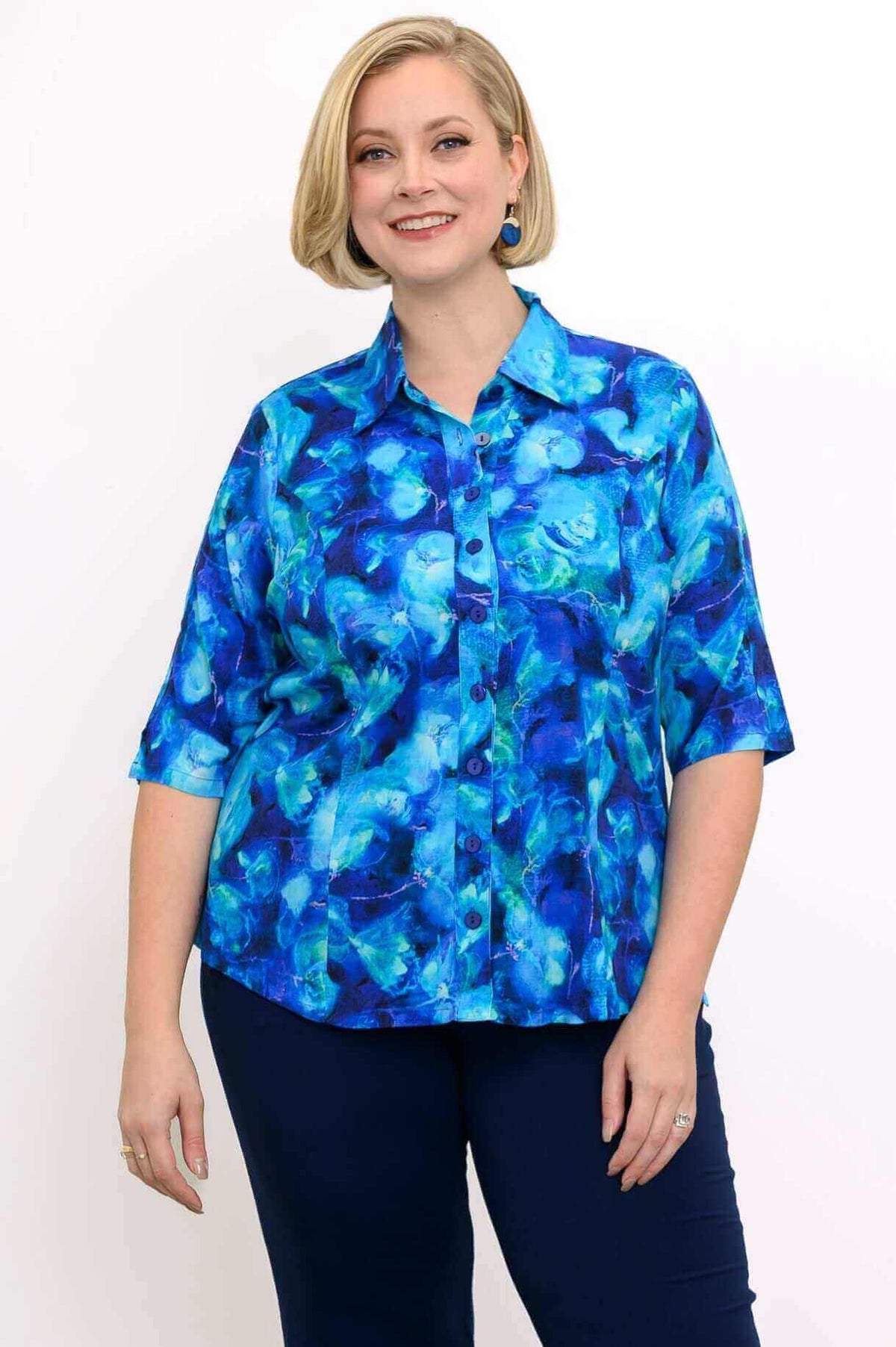 Model wearing a vibrant blue patterned blouse with short sleeves and a collar