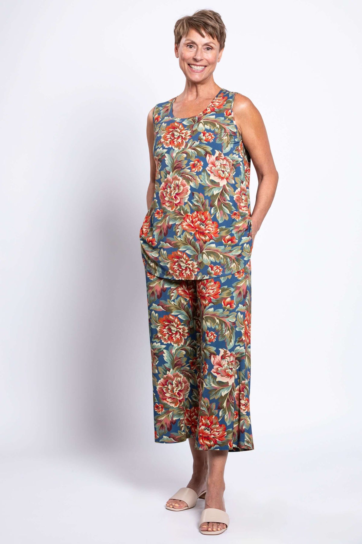 Woman smiling and posing hands-in-pockets in a vintage floral sleeveless tank top and matching pants, full body view