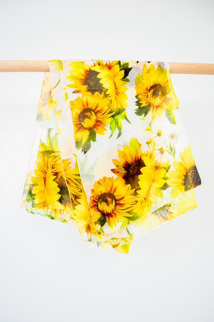 A large silk scarf with a sunflower pattern displayed on a white background, front view