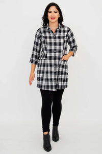 Model walking forward in plaid flannel tunic, black leggings, and ankle boots