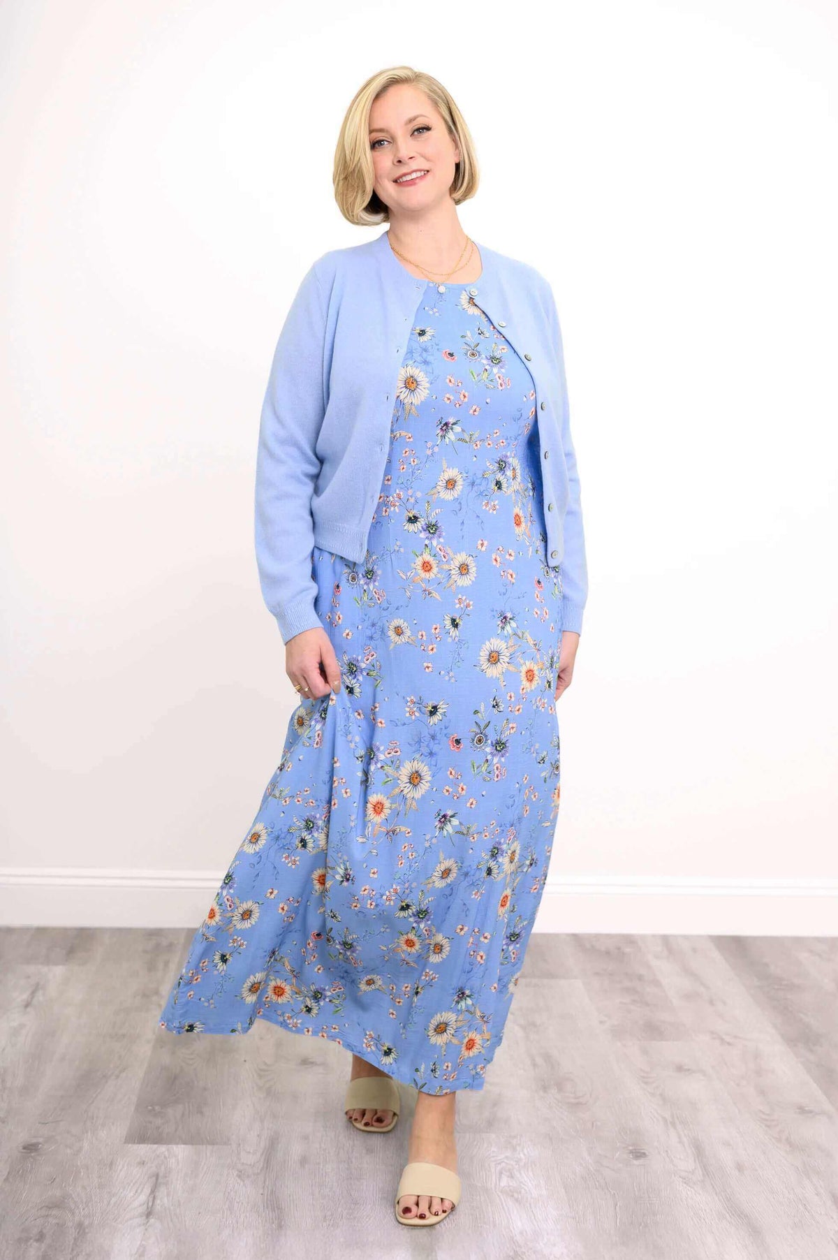 Model in blue floral maxi dress and light blue cardigan walking