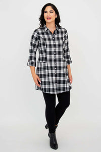 Front angled view of model walking in plaid flannel tunic and black leggings