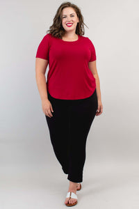 Woman walking in a crimson scoop neck tee and black pants, full body, front view