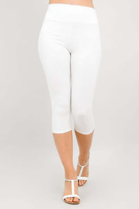 Walking view of model in white capri leggings with white heeled sandals