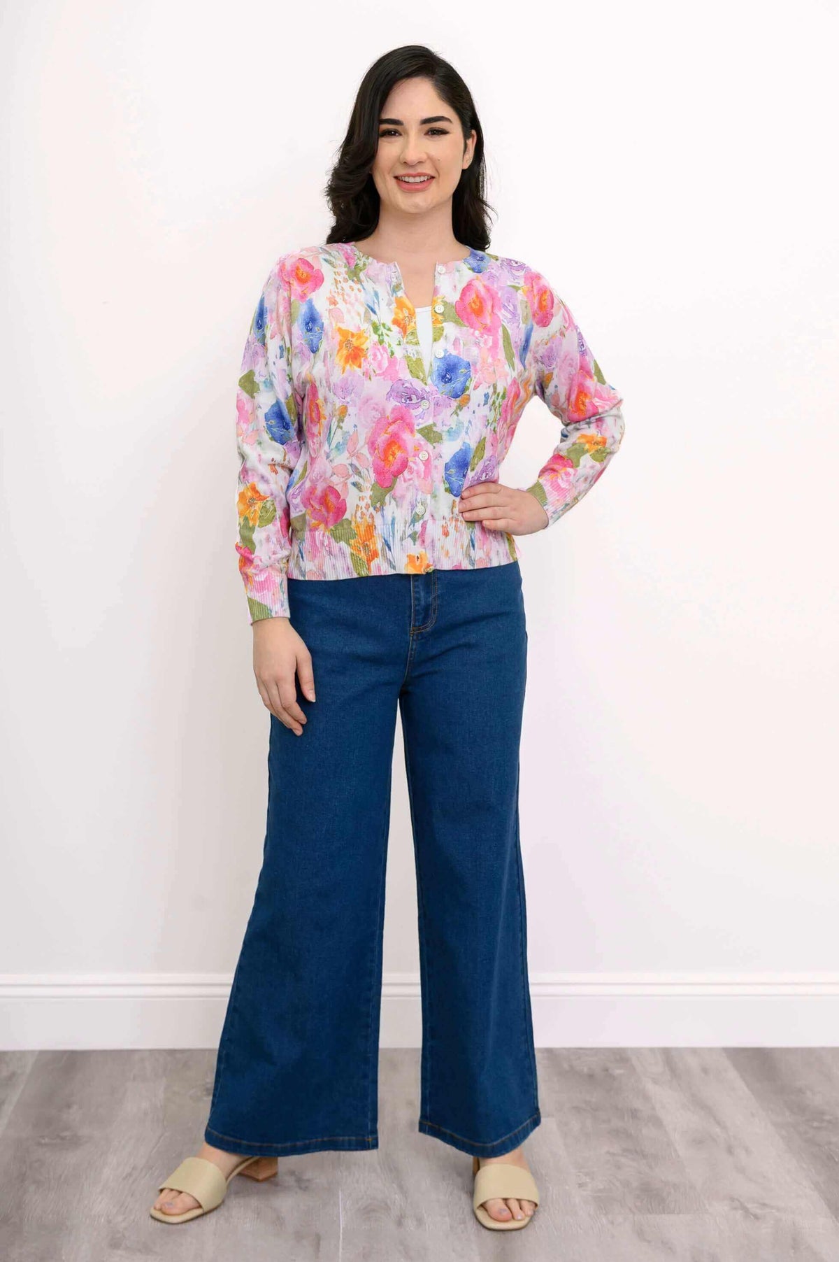 Woman standing in watercolor floral cardigan and blue jeans, hand on hip