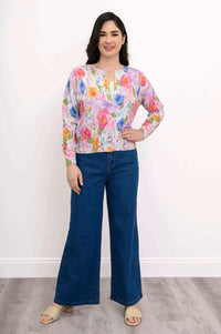 Woman standing in watercolor floral cardigan and blue jeans, hand on hip