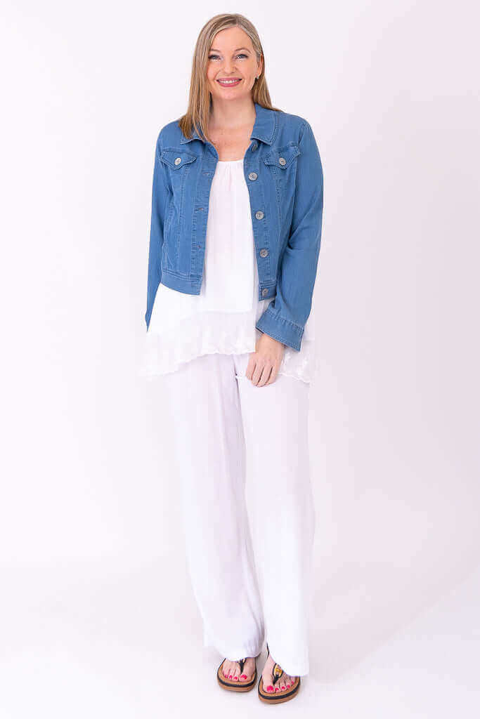 Woman wearing a white lace tank top, full-length, styled with a blue denim jacket