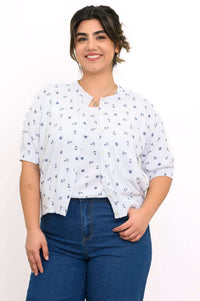 Woman wearing a white short-sleeve cardigan with navy nautical anchors and wheels pattern