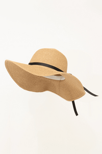 Wide brim sun hat in tan with flowing black ribbon viewed from the side