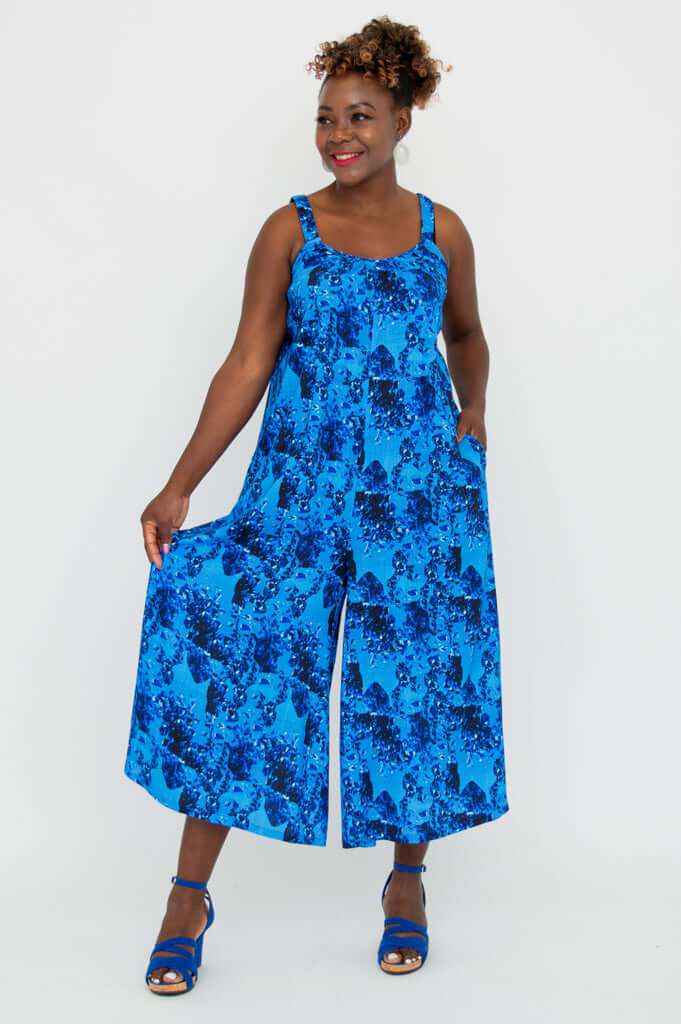 Woman showing the wide cropped hem of a blue floral jumpsuit