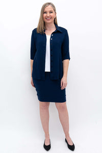 Woman smiling and wearing a navy pencil skirt styled with a button-up shirt and heels