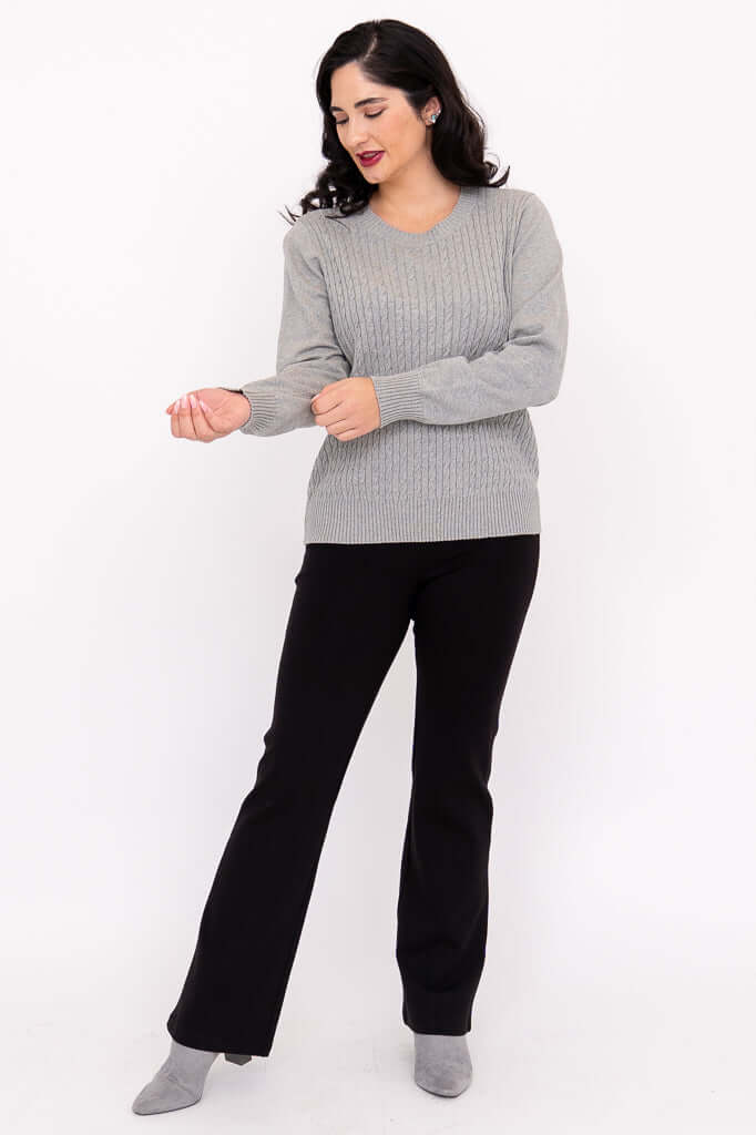 Woman adjusting sleeve of grey cable knit sweater