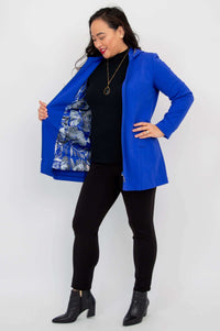 Woman opening cobalt blue coat to reveal a blue patterned inner lining