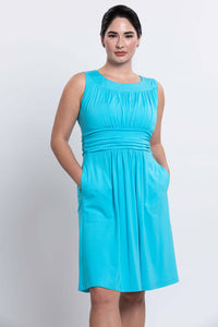 Woman showing side pockets on aqua blue dress with ruched detailing