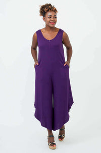 Woman in sleeveless purple jumpsuit with hands in pockets, highlighting side pockets and flowy legs