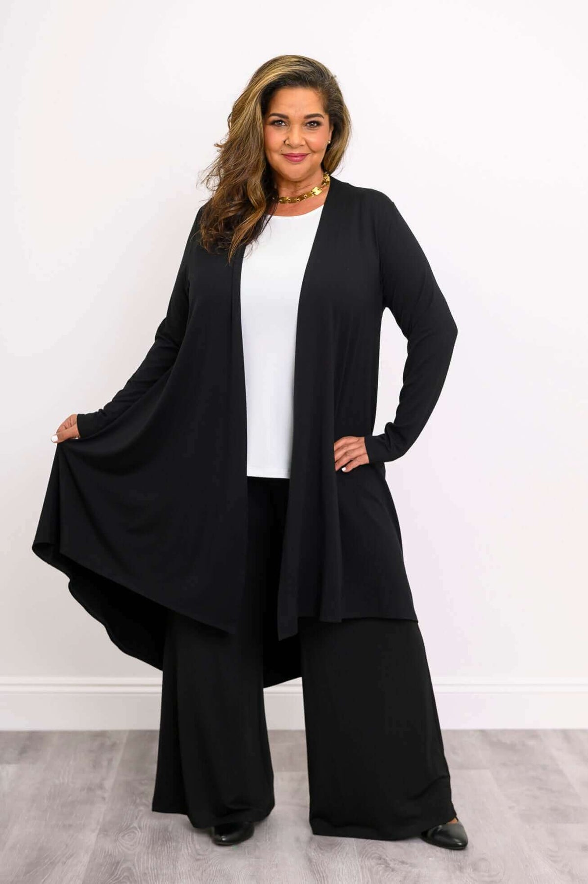 Woman displaying the length and flare of a black bamboo long cardigan, front view