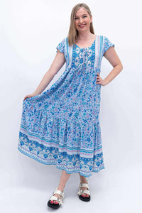 Woman holding out the skirt of a blue floral maxi Sharpie Dress