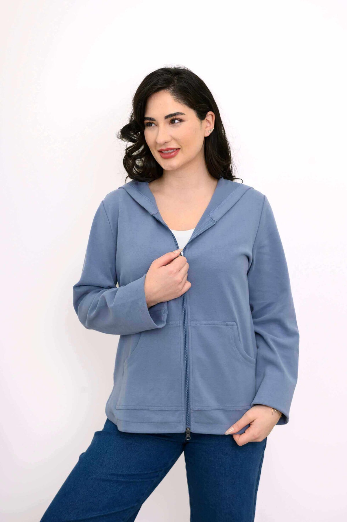 Woman in blue hoodie jacket partially unzipped, facing front and looking aside