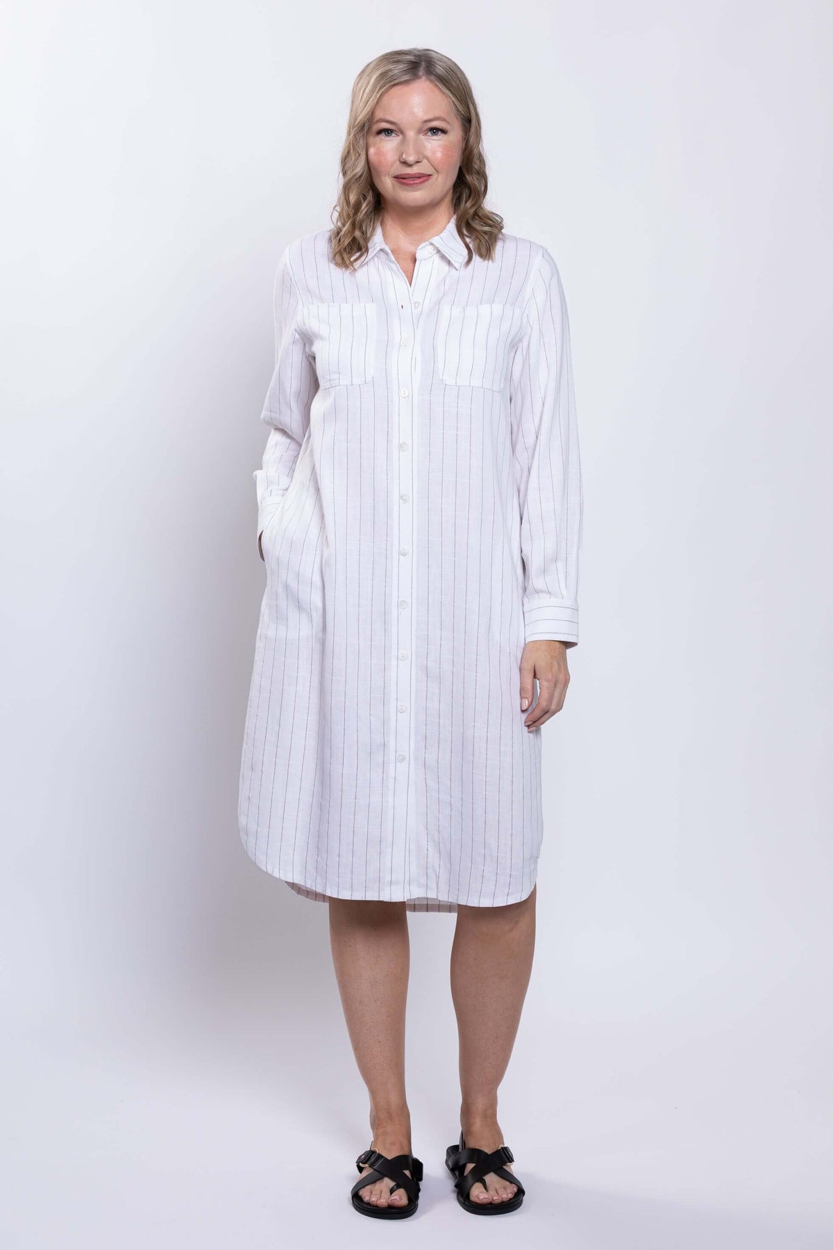 Woman facing forward in a striped shirt dress with long sleeves and pockets