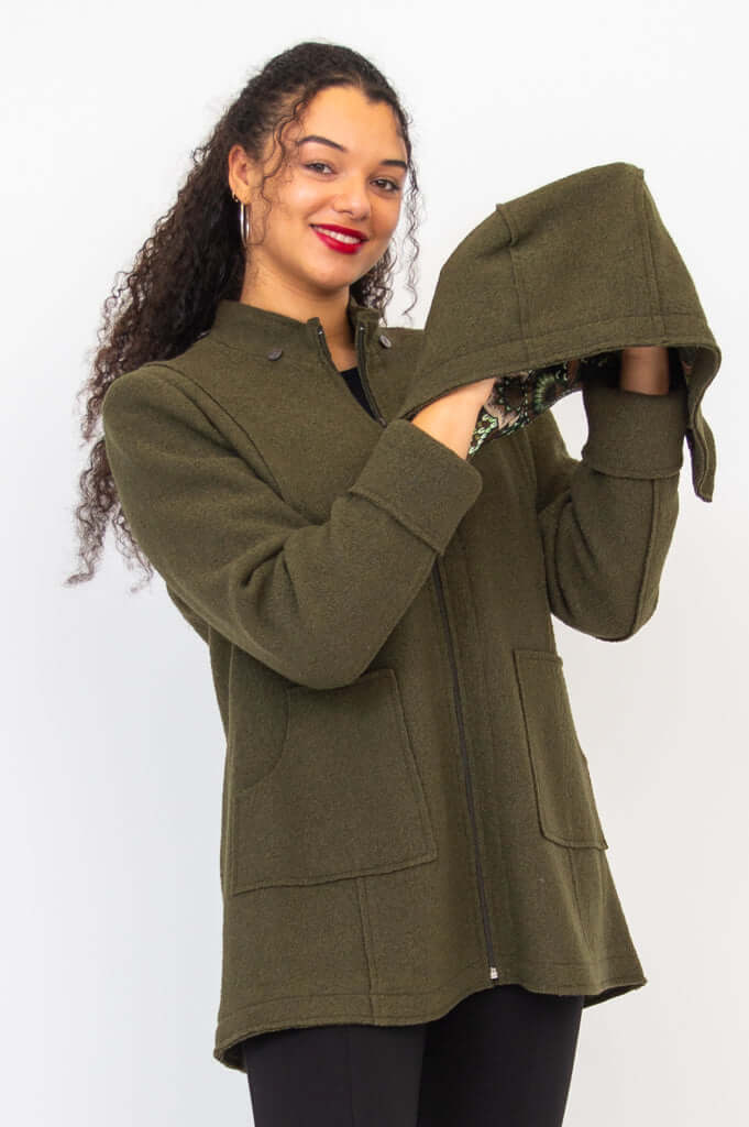 Woman holding detachable hood of olive green wool blend coat