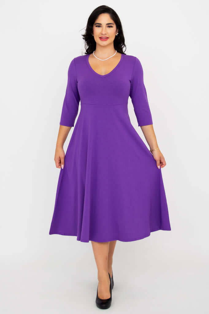 Woman holding out the skirt of a purple A-line midi dress, highlighting its flow