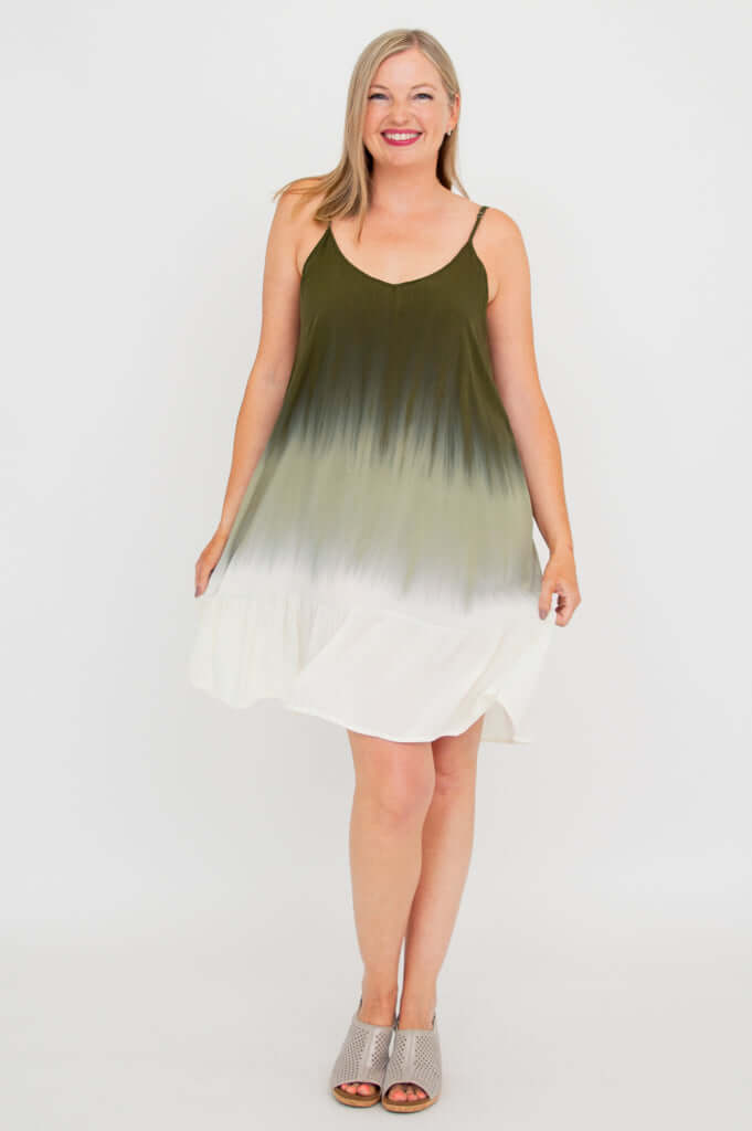 Woman holding out the skirt of an olive ombre mini dress, front view