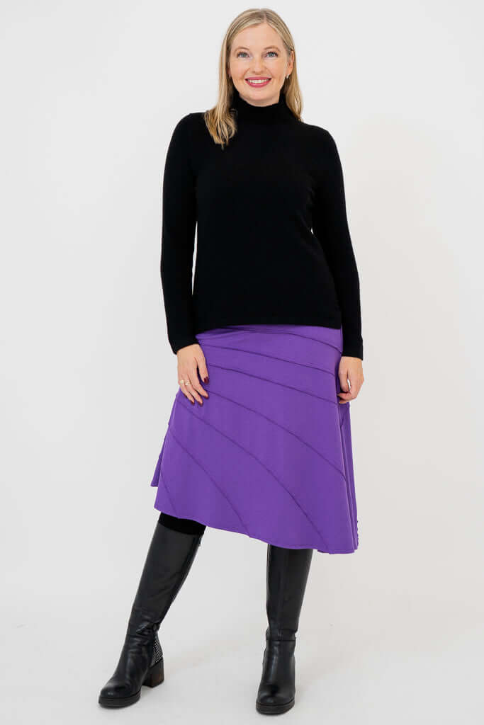 Woman wearing Beverly Skirt in purple and black sweater, relaxed pose