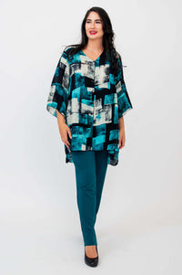 Woman standing with hands at sides in Darla blouse and teal pants, front view