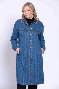 Woman smiling in long blue denim jacket with hands in pockets