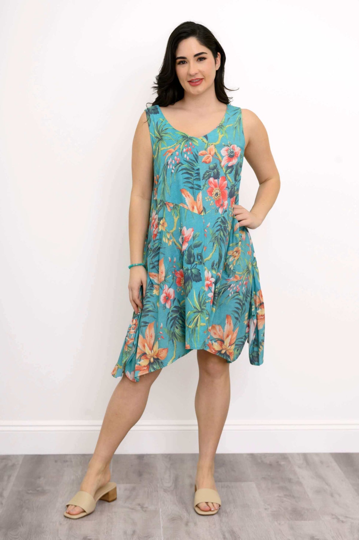 Woman modeling turquoise floral dress and beige sandals, full body view