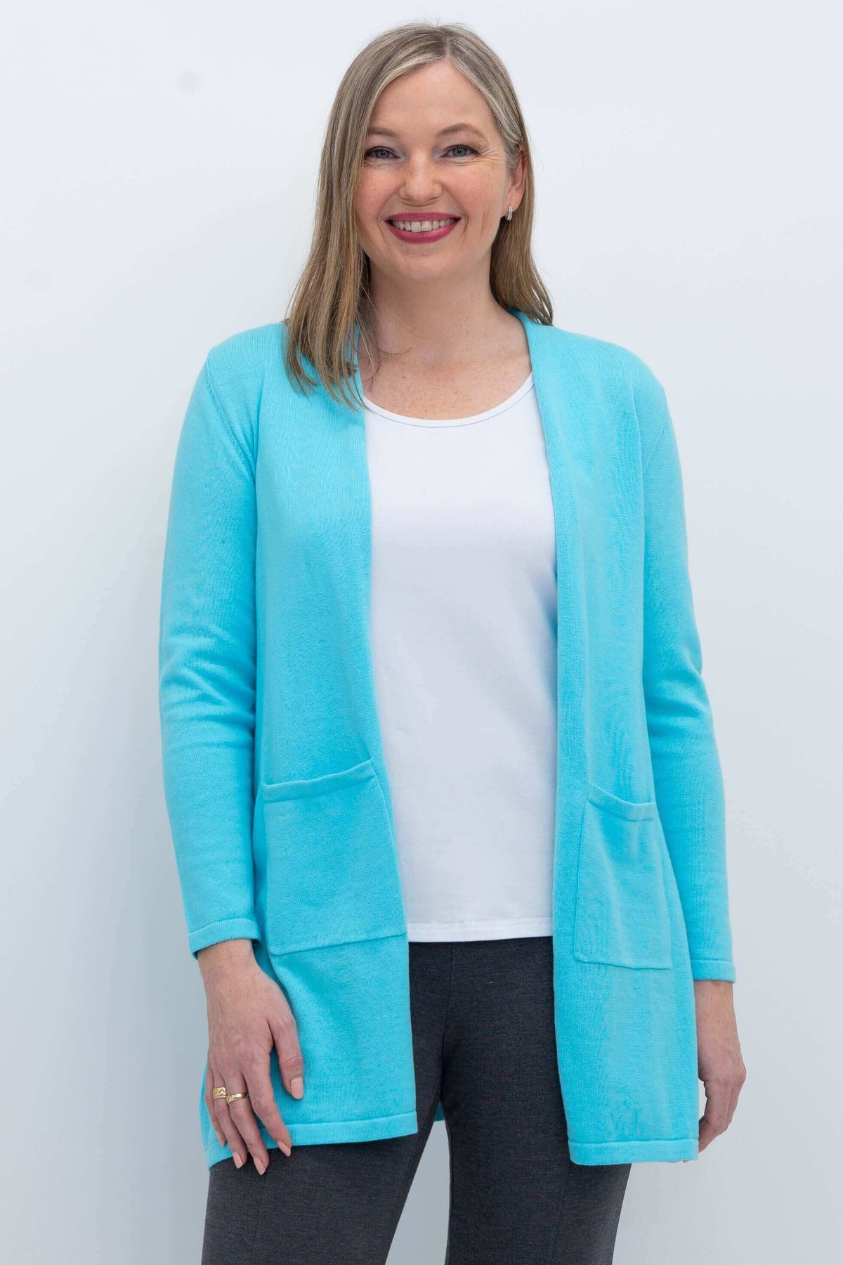 Woman wearing an aqua blue open cardigan sweater with patch pockets, front view