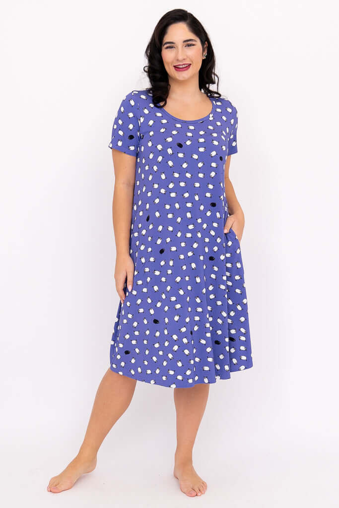 Woman wearing a purple polka dot short-sleeve sleepshirt, standing and smiling
