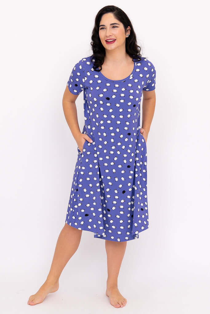 Woman standing with hands in pockets, wearing a purple polka dot sleepshirt