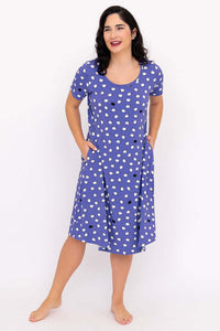 Woman standing with hands in pockets, wearing a purple polka dot sleepshirt