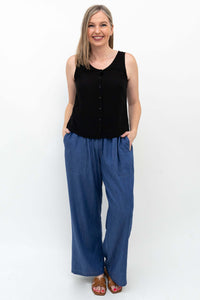 Woman wearing black sleeveless top and wide-leg blue denim Tencel pants with hands in pockets