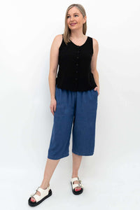 Woman in blue denim Tencel capris and black sleeveless top smiling