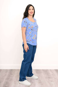 Woman in a blue floral rounded-hem tee and blue jeans, side view