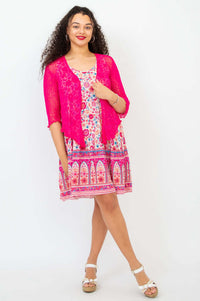 Woman in a floral sleeveless dress and pink lace cardigan smiling